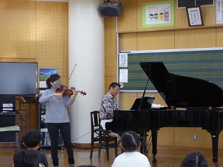 小学校アウトリーチコンサートでヴァイオリン奏者とピアノ奏者が演奏する様子